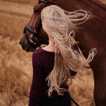 blonde woman with horse looking away